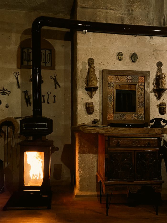 Cozy rustic room with a fireplace stove and antique decorations on the wall.